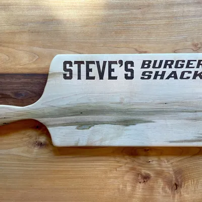 A personalized serving board engraved with "Steve's Burger Shack".