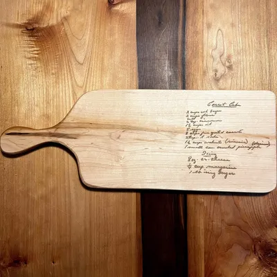 A solid wood serving board that has a handwritten recipe engraved on in.