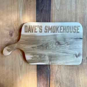 A personalized serving board engraved with "Dave's Smokehouse".